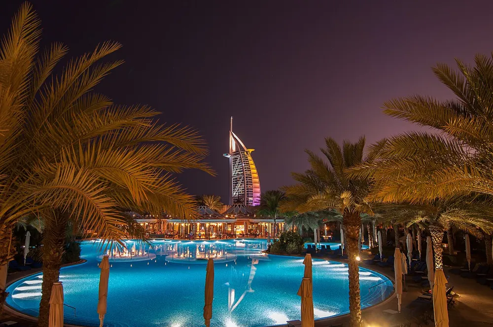 Burj Al Arab seen across a palm-lined pool at night